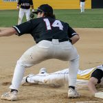 Base runner, Dylan Green, dives back to first base to avoid being picked off.