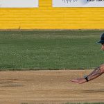 Baserunner, Colby Rafail, begins his dive into second base as the ball sails through the air toward the shortstop covering the base.