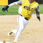 Base runner, Adam Reyes, rounds third base while looking to left field for the incoming play at home.