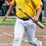 Bat boy running back to the dugout from home plate with a bat in hand.