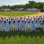 Elevated drone shot of the 2023 Redding Colt 45s team standing three rows deep, in the shallow outfield, behind second base, with home plate and the stands in the background.