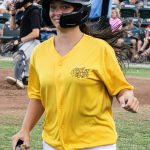 Colt 45s batgirl, Lacie, smiling and marching back to the dugout with bat in hand (photographed by Bill Wagner on 2026-07-11).