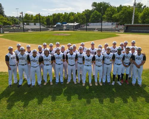 Elevated drone shot of the 2023 Redding Colt 45s team standing three rows deep, in the shallow outfield, behind second base, with home plate and the stands in the background.
